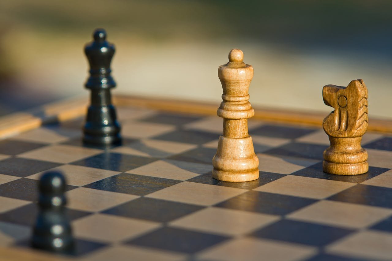 Detailed view of chess pieces on a classic wooden chessboard outdoors.